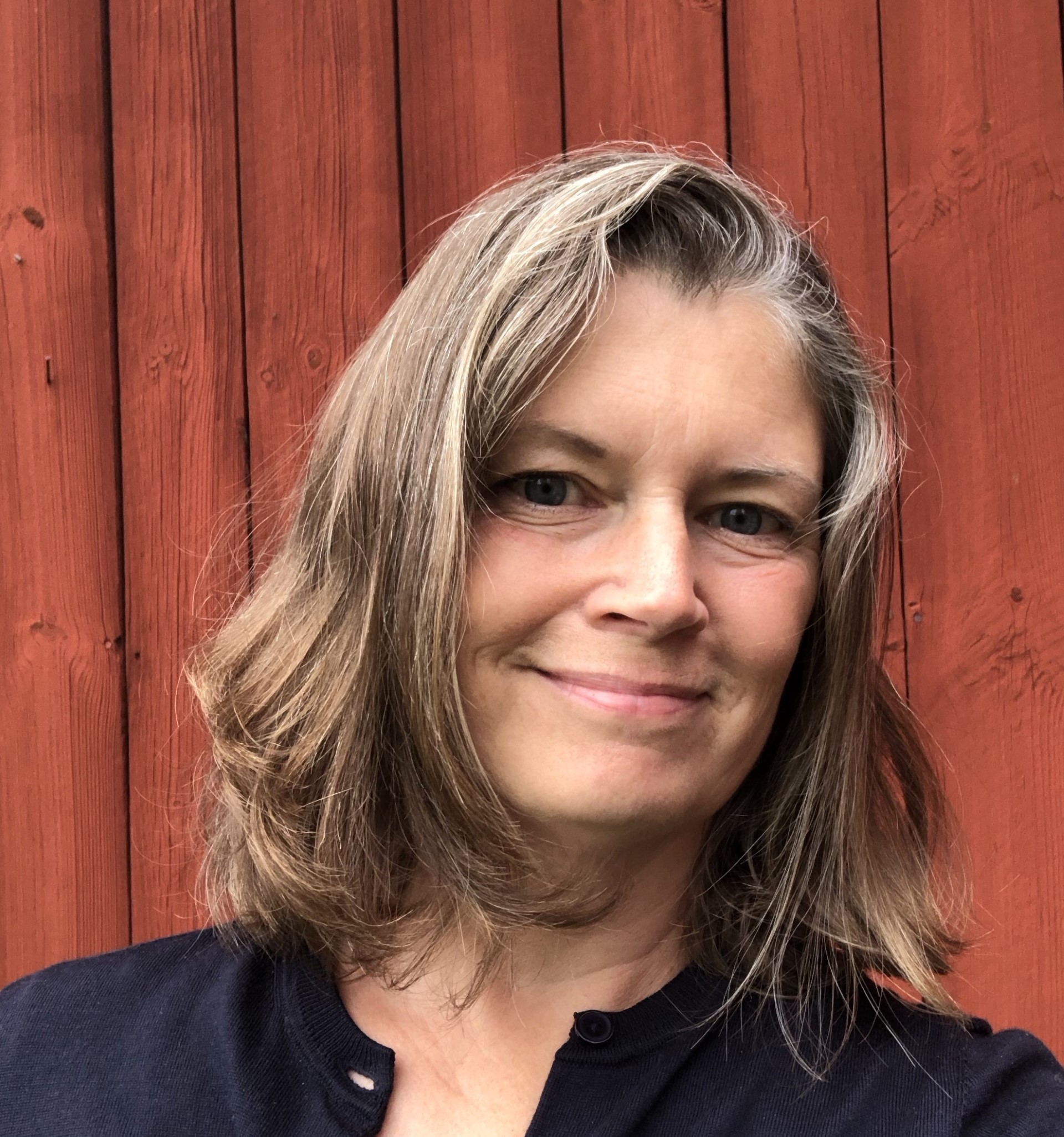 Smiling woman in front of a red barn wall